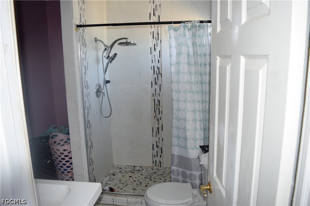 17 Colorado Road Lehigh Acres, FL 33936 - Photo 15 of 17 a bathroom with a shower curtain and a toilet