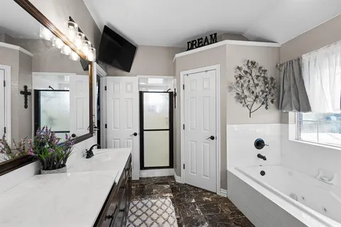 a bathroom with a bathtub a sink and a large mirror