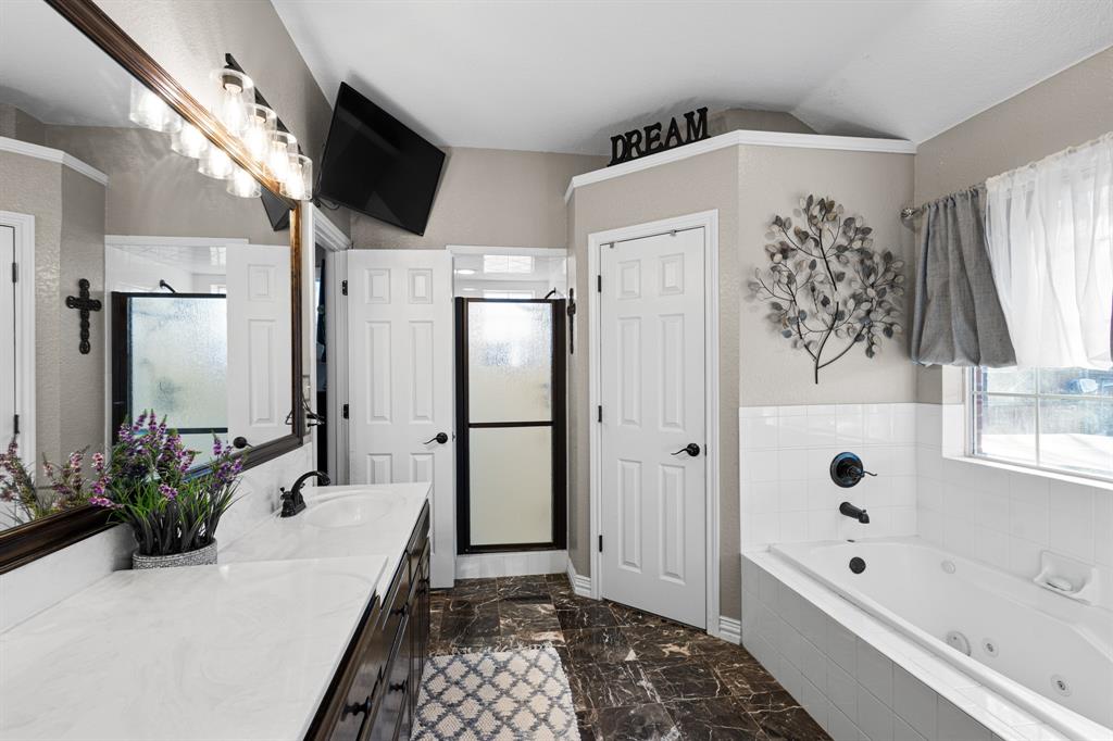 1701 Oakmeadow Drive Decatur, TX 76234 - Photo 20 of 39 a bathroom with a bathtub a sink and a large mirror
