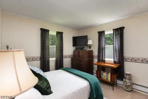 a bedroom with a bed and a flat tv screen on dresser
