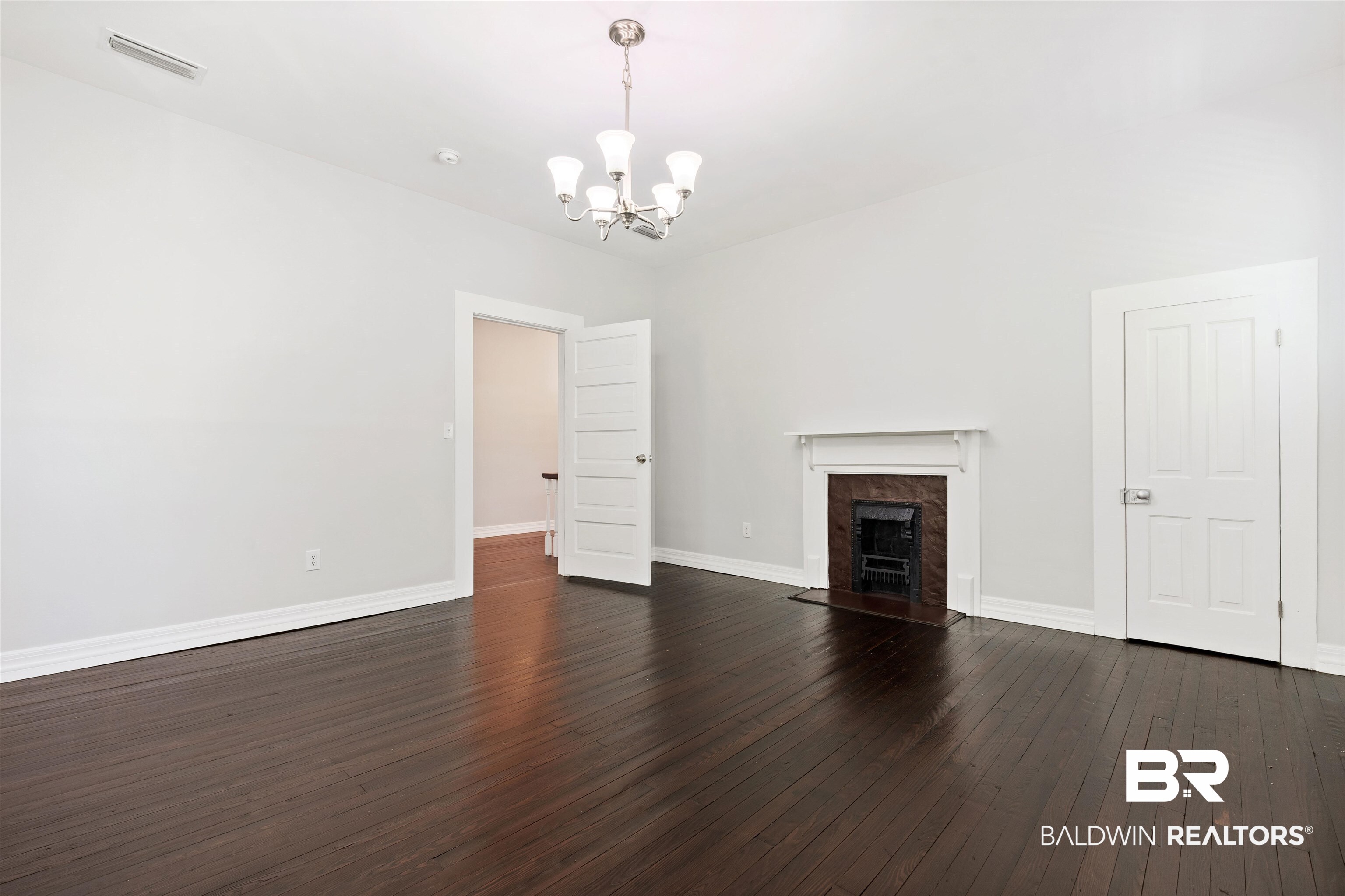 407 East 2nd Street Bay Minette, AL 36507 - Photo 23 of 40 Unfurnished living room featuring dark wood-style floors, a premium fireplace, and a chandelier