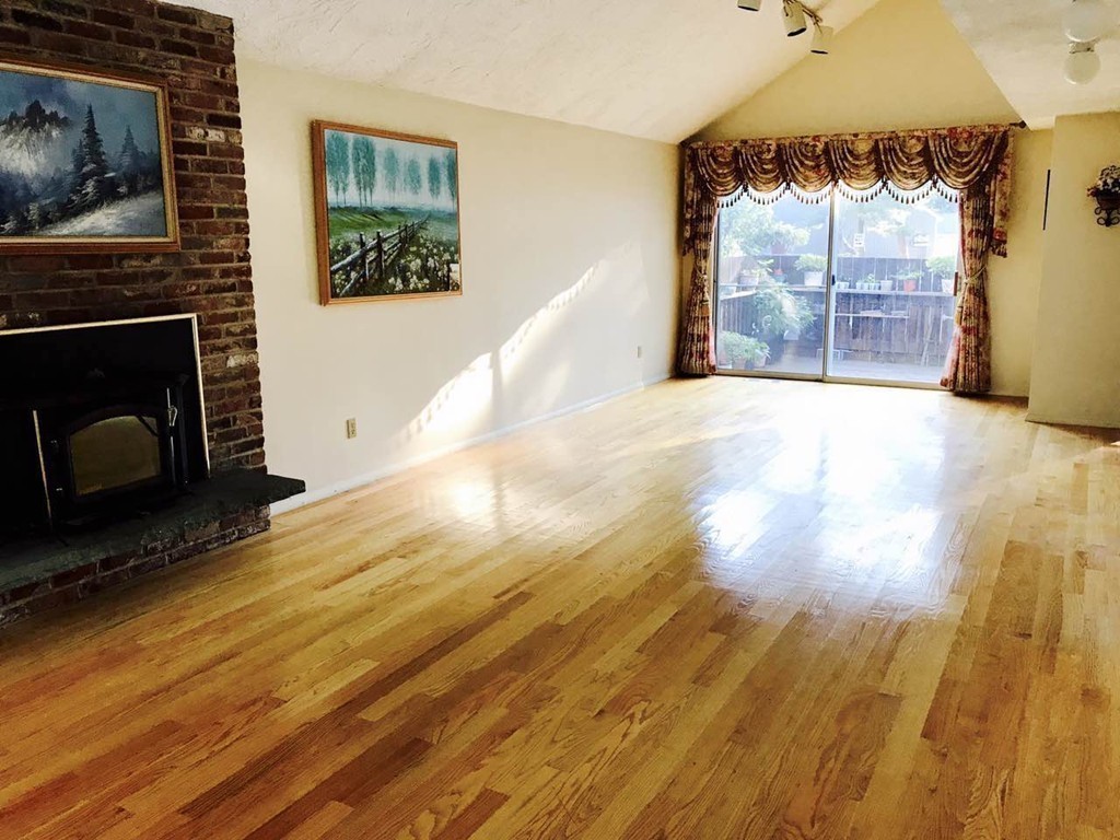 134 Russet Lane, Unit 134 Boxborough, MA 01719 - Photo 3 of 16 a view of empty room with wooden floor and fireplace