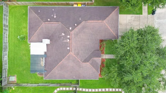an aerial view of a house with a yard and trees all around