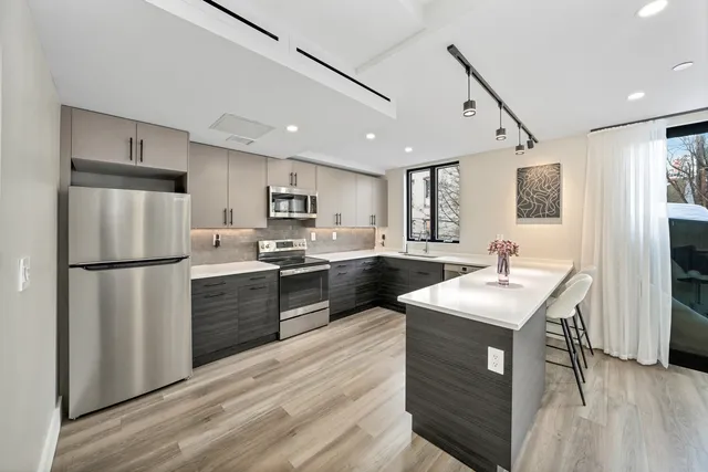 a kitchen with a refrigerator a sink and a stove top oven with wooden floor