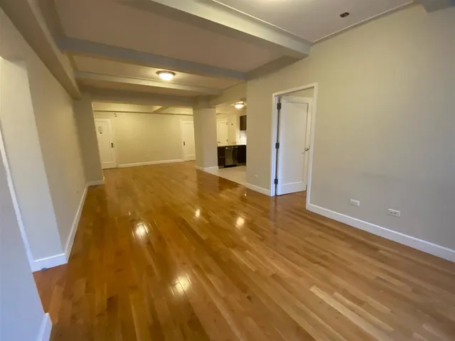 a view of a big room with wooden floor and windows