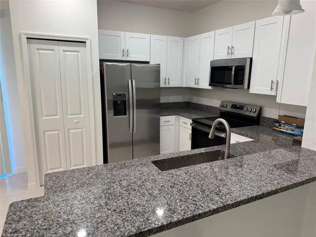 a kitchen with stainless steel appliances granite countertop a sink a stove and a microwave