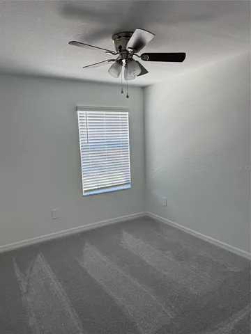 an empty room with a ceiling fan and window