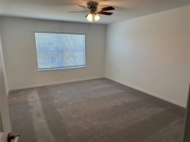 an empty room with a window and a fan