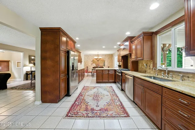 a large kitchen with stainless steel appliances kitchen island granite countertop a refrigerator and a sink