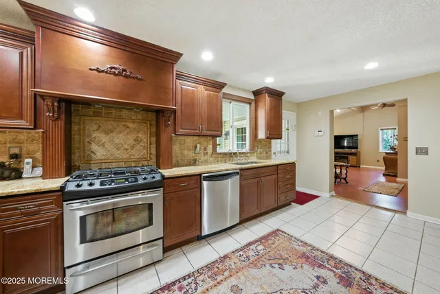 a large kitchen with stainless steel appliances granite countertop a stove a sink and a refrigerator