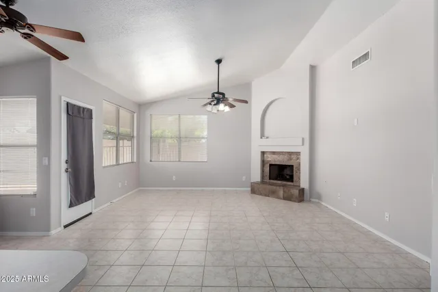 an empty room with windows and fireplace