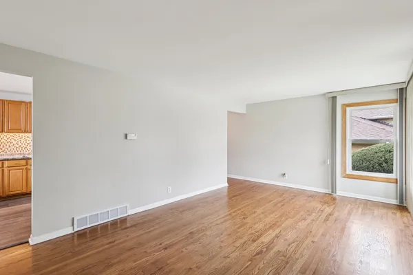 a view of an empty room with wooden floor and windows