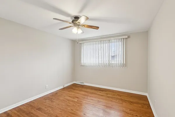 an empty room with wooden floor fan and windows