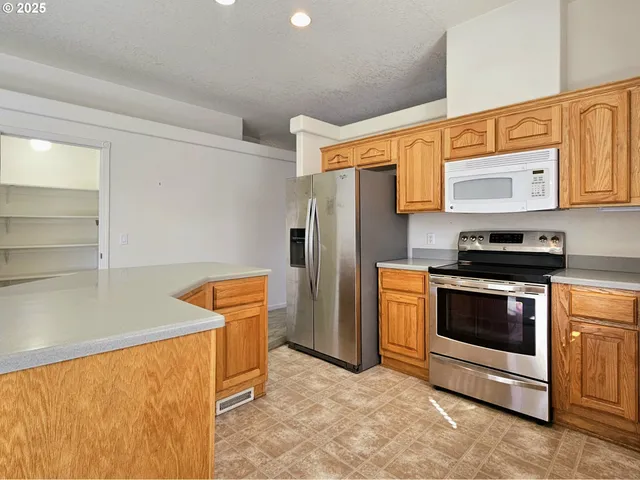 a kitchen with stainless steel appliances granite countertop a refrigerator a stove and a sink