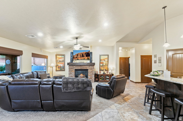 210 Talon Court Ivins, UT 84738 - Photo 15 of 60 Living area with lofted ceiling, a ceiling fan, and a stone fireplace