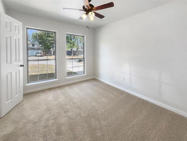 an empty room with windows and fan