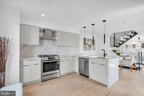 a kitchen with stainless steel appliances a sink a stove a refrigerator and white cabinets