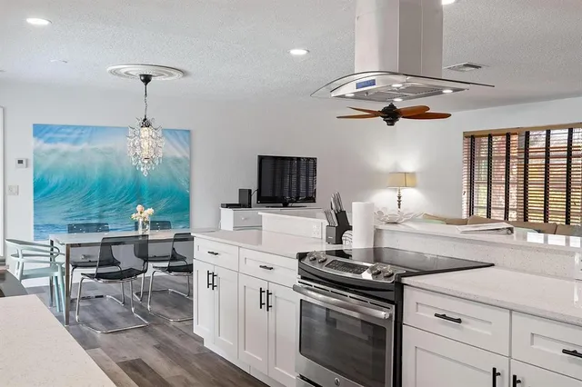 a kitchen with a stove a chandelier and a view of dining room