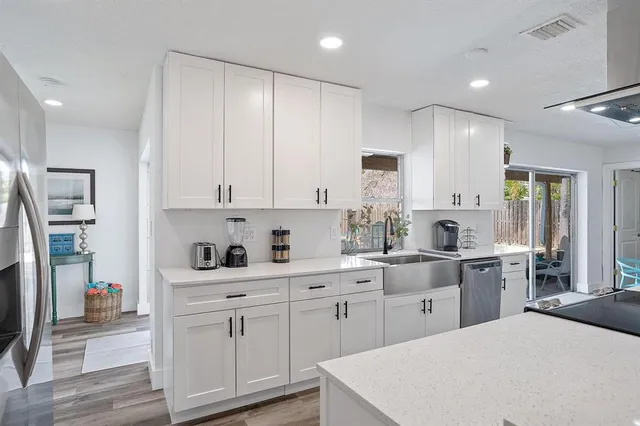 a kitchen with white cabinets and sink