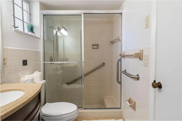 a bathroom with a granite countertop bathtub shower sink vanity and toilet