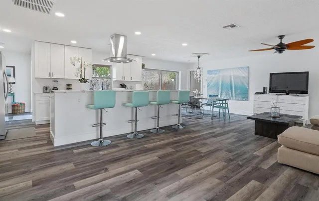 a living room with furniture a flat screen tv and kitchen view