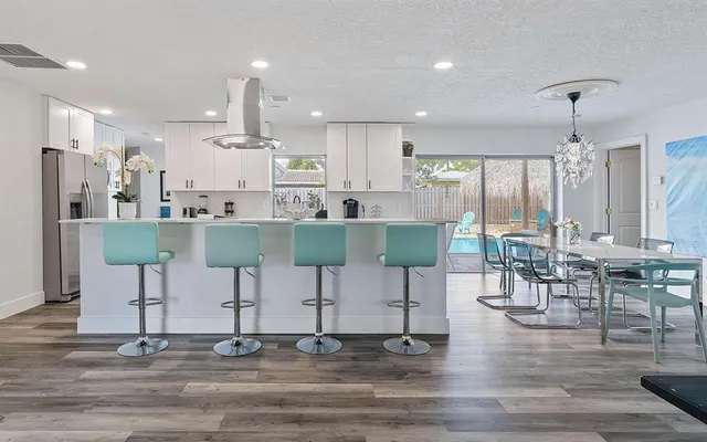 a kitchen with stainless steel appliances kitchen island granite countertop a dining table chairs and white cabinets