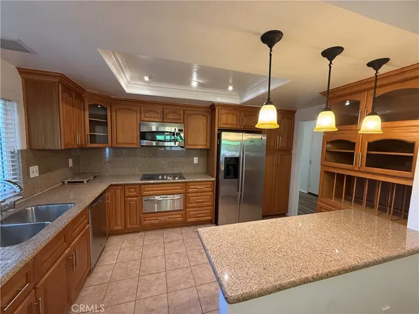a kitchen with stainless steel appliances granite countertop a sink a stove top oven a refrigerator and dishwasher