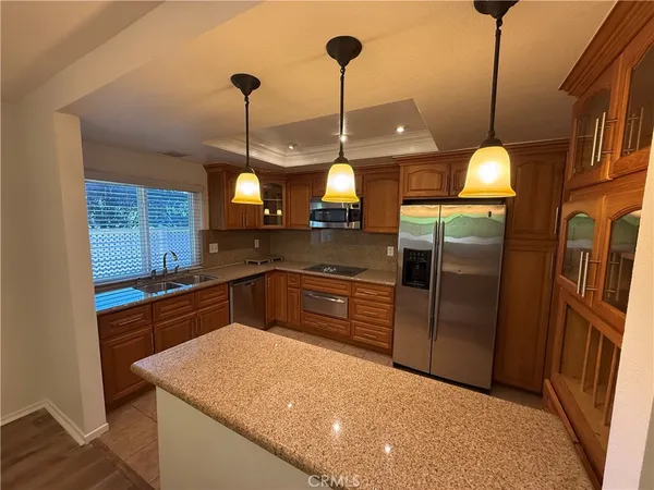 a kitchen with stainless steel appliances granite countertop a sink a refrigerator a stove and a wooden floor