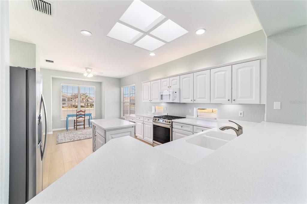 9612 Southeast 124th Loop Summerfield, FL 34491 - Photo 23 of 60 a kitchen with granite countertop a stove a sink a refrigerator and white cabinets with wooden floor