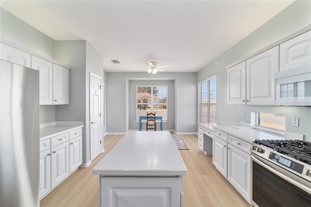 9612 Southeast 124th Loop Summerfield, FL 34491 - Photo 25 of 60 a kitchen with stainless steel appliances a white stove top oven a sink dishwasher and a refrigerator with wooden floor