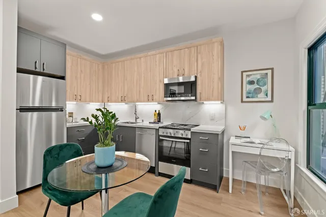 a kitchen with stainless steel appliances granite countertop a stove a refrigerator a sink a dining table and chairs with wooden floor