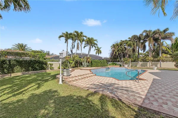 a view of a swimming pool with a yard and palm trees