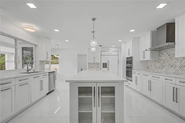 a large kitchen with granite countertop a white stove top oven and white cabinets