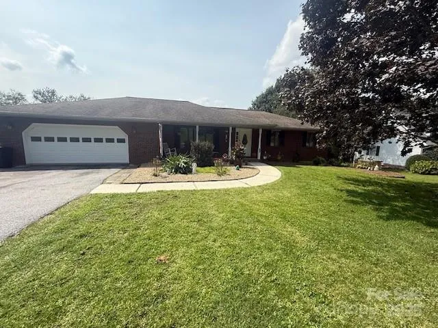 a front view of house with yard and trees in the background