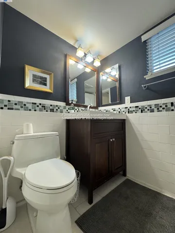 a bathroom with a toilet a sink a mirror and a window