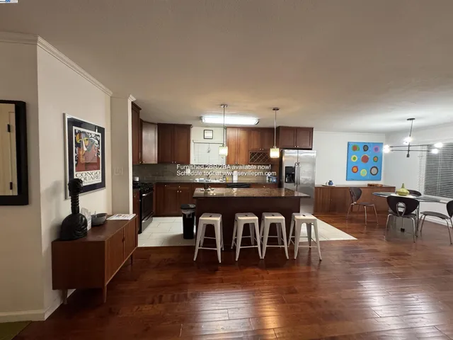 a living room with furniture a wooden floor and a kitchen view