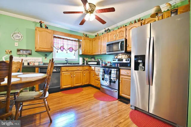 a kitchen with stainless steel appliances granite countertop a refrigerator a sink dishwasher a stove and a dining table with wooden floor