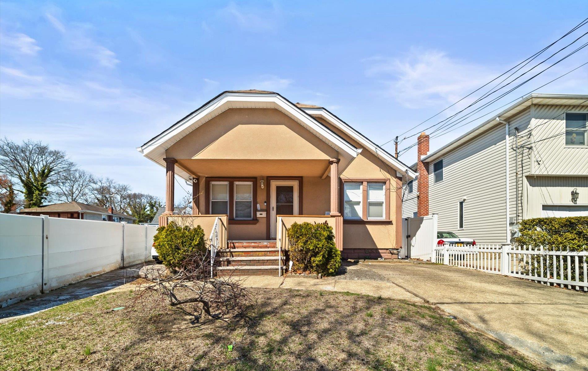 View of front facade featuring a porch, stucco siding, and fence