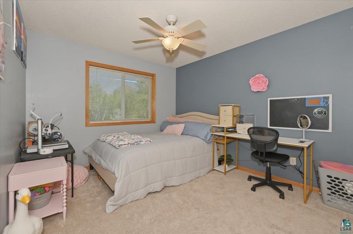 47 Amy Lane Esko, MN 55733 - Photo 21 of 33 Bedroom featuring a window with natural wood trim, plush carpeting, and a ceiling fan with integrated lighting