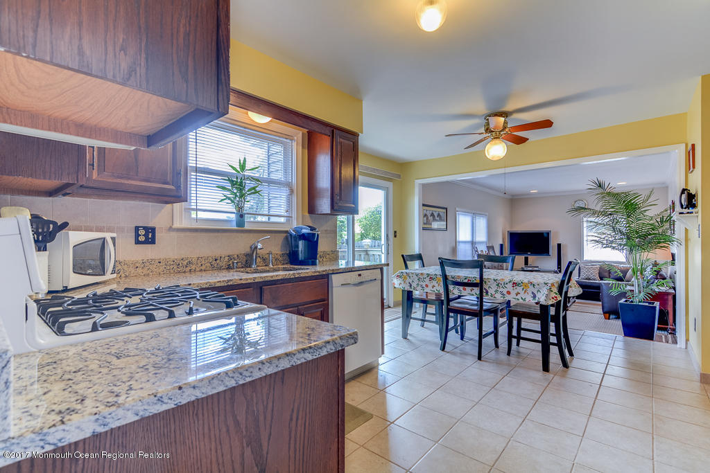 173 Club House Road Brick, NJ 08723 - Photo 16 of 30 a kitchen with stainless steel appliances granite countertop a stove top oven a sink a dining table and chairs with wooden floor