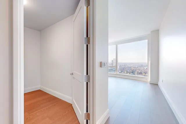 a view of a hallway with wooden floor and a bathroom