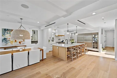 a large white kitchen with a large island oven a sink stainless steel appliances and cabinets