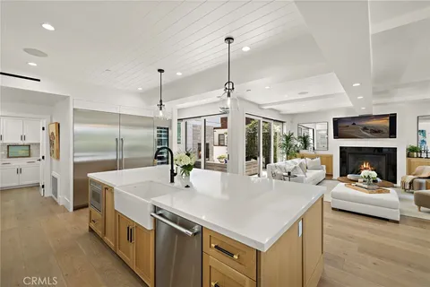 a large white kitchen with a stove a sink a refrigerator and a fireplace