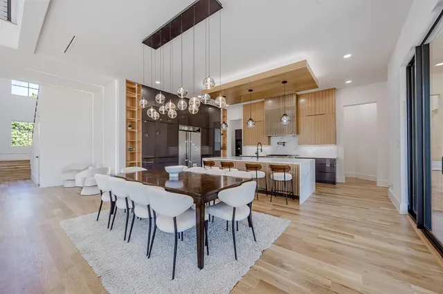 a dining hall with stainless steel appliances granite countertop wooden floor a dining table and chairs