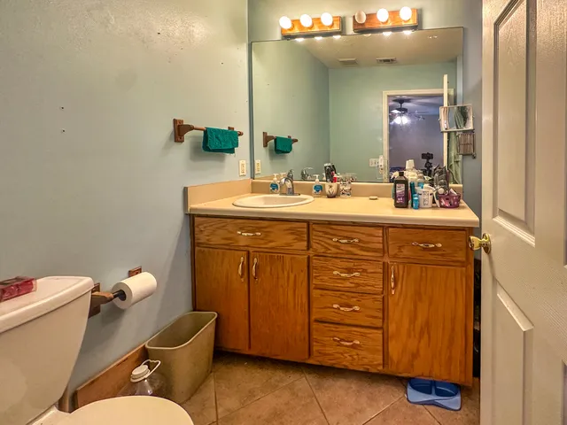 a bathroom with a granite countertop toilet sink and mirror