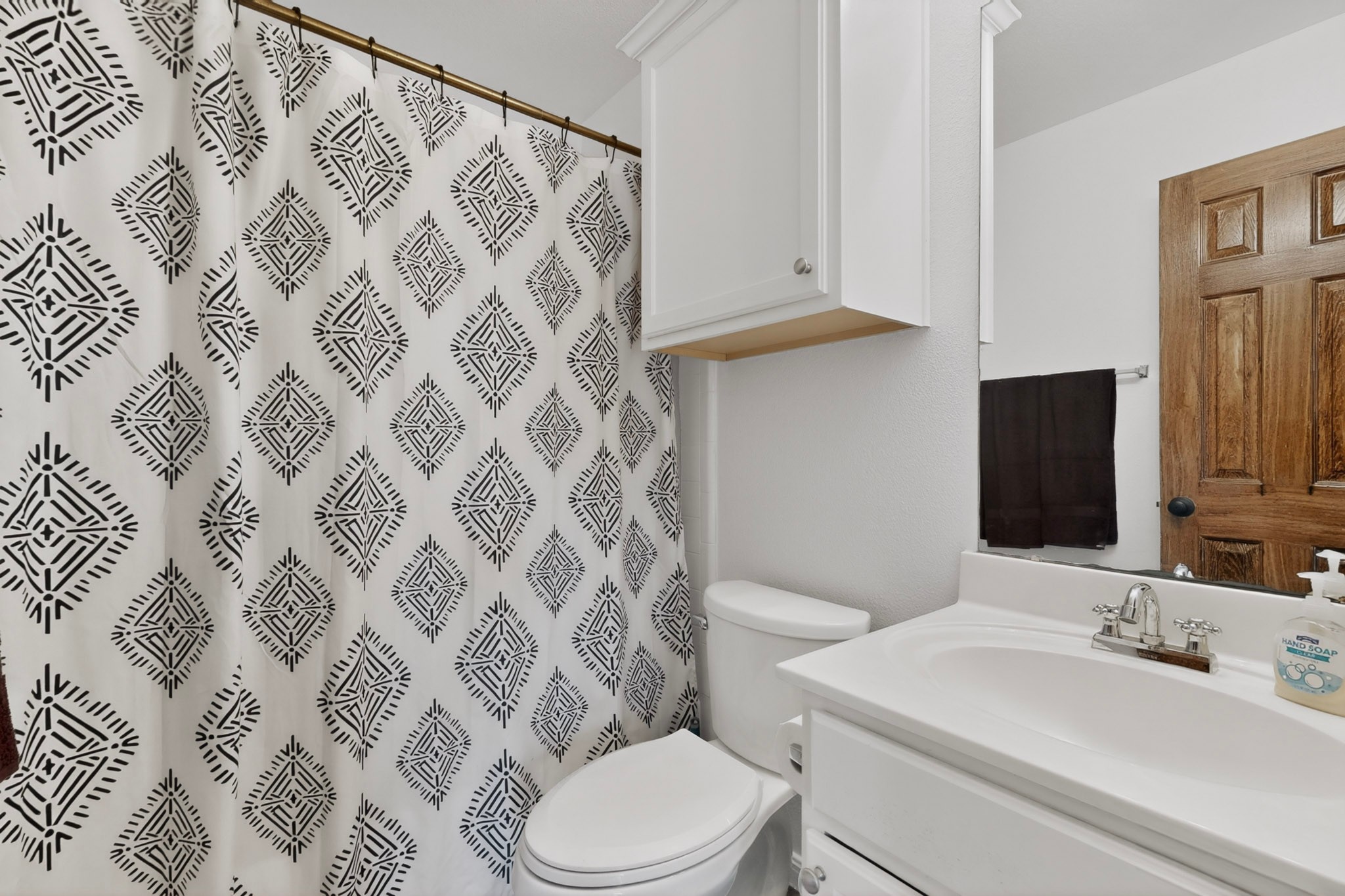 15104 Mimebark Way Austin, TX 78724 - Photo 26 of 38 Bathroom featuring a white vanity with integrated sink, chrome faucet, white cabinetry, and a panel door with dark hardware