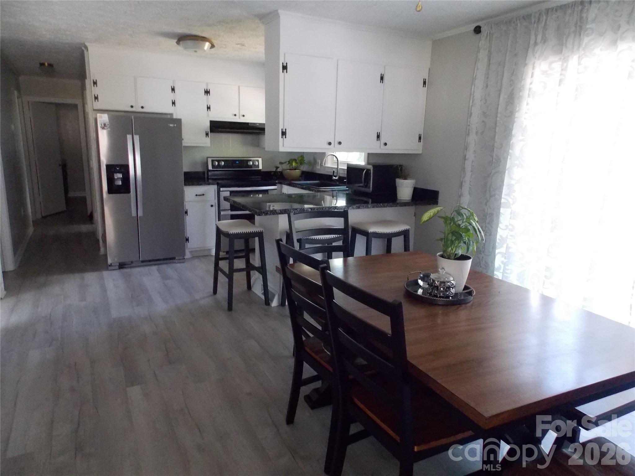 1380 May Road Granite Falls, NC 28630 - Photo 6 of 26 a kitchen with stainless steel appliances a table chairs and a refrigerator