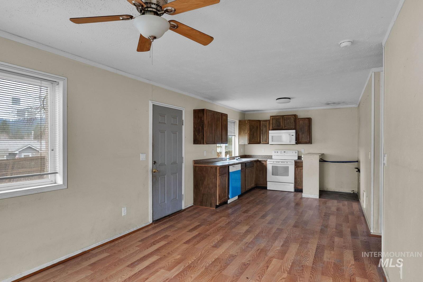 4715 West Reeves Street Coeur D'Alene, ID 83814 - Photo 7 of 24 Kitchen with white appliances, crown molding, dark brown cabinetry, dark wood-style flooring, and a ceiling fan