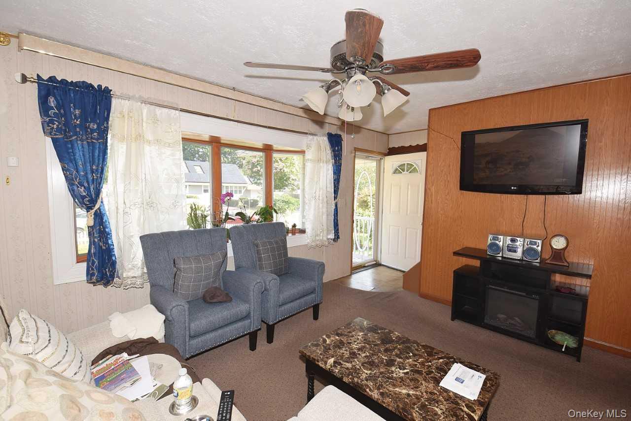 14 East Walnut Street Central Islip, NY 11722 - Photo 3 of 18 a living room with furniture a flat screen tv and a chandelier