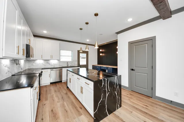 a kitchen with stainless steel appliances granite countertop a sink a stove and a refrigerator